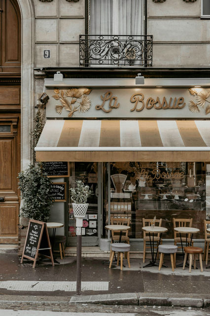 The La Bossue bakery storefront with striped awning and outdoor tables in Paris
