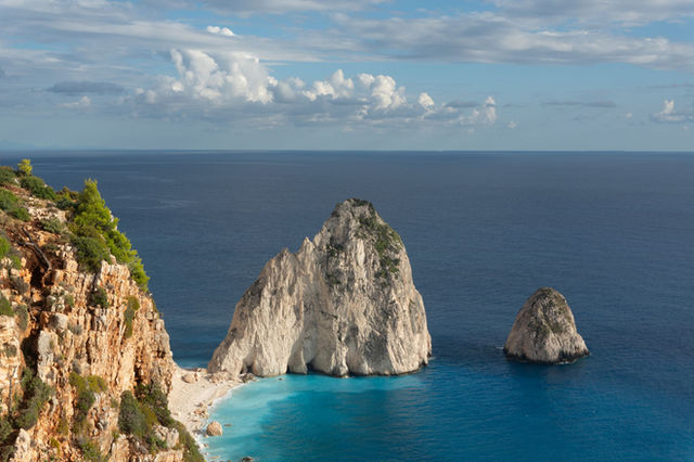 Breathtaking view of Zakynthos cliffs with blue sea and unique rock formations under a partly cloudy sky.