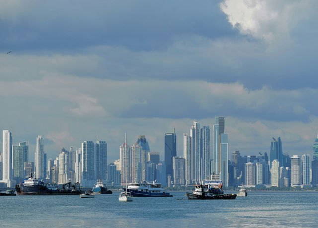 Modern skyscrapers rise above a bay with boats.