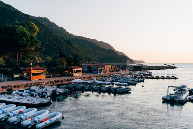 Enjoy a serene view of a marina with speedboats docked in Corsica, France, during sunset.