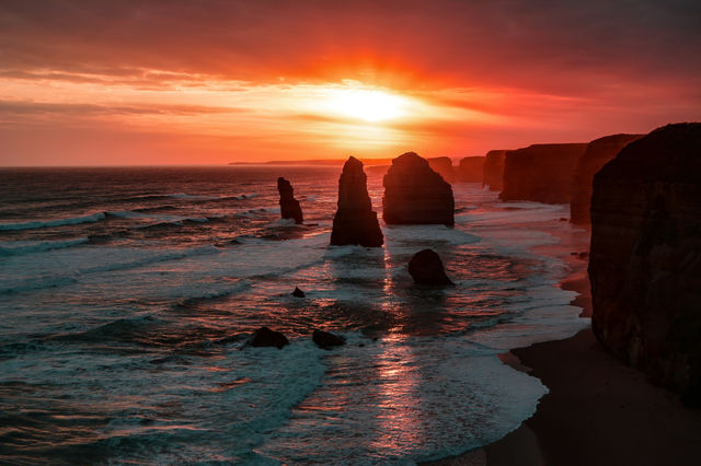 The 12 Apostles monoliths in the ocean under a warm orange sky in Victoria