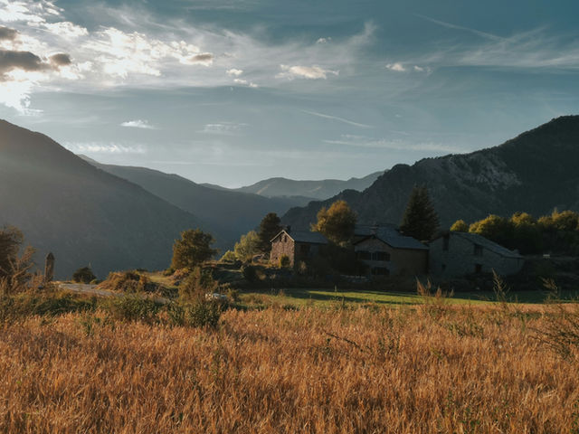 a field with a house and mountains in the background