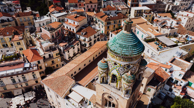 High-angle view of Amalfi, Italy, highlighting the ornate cathedral dome and vibrant townscape.