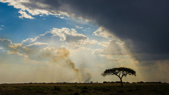 Rainclouds, fire over african landscape