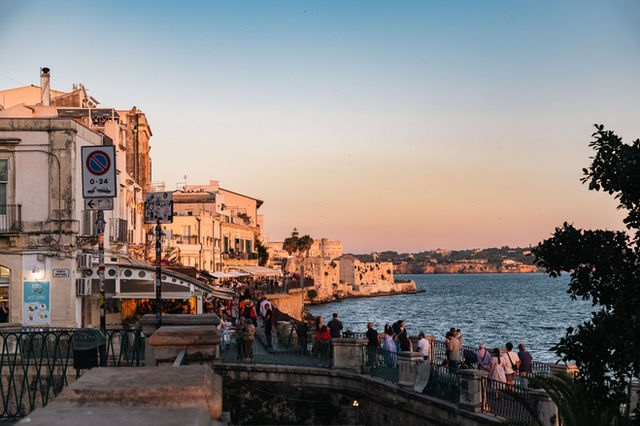Charming sunset over the scenic promenade in Syracuse, Sicily, with coastal views and historic architecture.