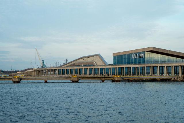 A striking view of the modern Tallinn Cruise Terminal at the Port of Tallinn, showcasing sleek contemporary architecture and the expansive seaside promenade against the calm blue waters of the Baltic