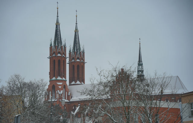 Brick church with spires on a snowy day.