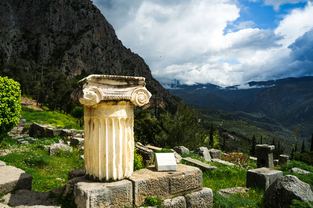 Ancient greek ruins with a column and mountains.