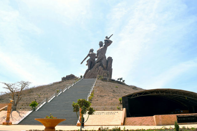 A statue of a man with a gun in front of a building