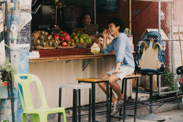 A lively street vendor in Chiang Mai selling fresh fruits with a smiling customer, exuding local charm.