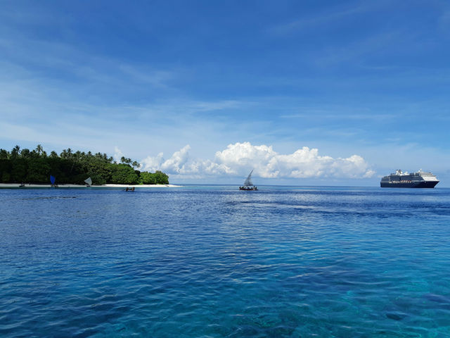 green trees on island surrounded by sea under blue and white cloudy sky during daytime