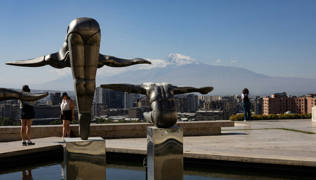 Sculptures overlook city with snow-capped mountain background