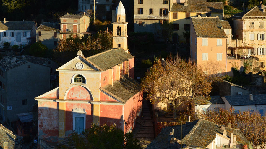 Picturesque village view of Nonza, Corsica with historic buildings under warm sunlight.