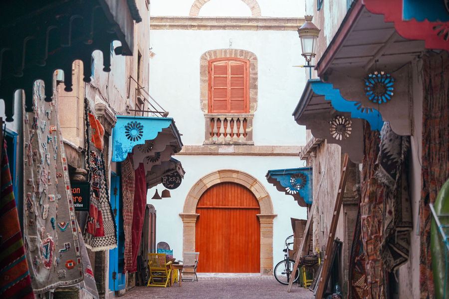 Vibrant textiles and traditional architecture in Essaouira's medina souk, Morocco.