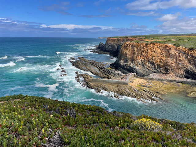 Breathtaking view of rocky cliffs and the Atlantic Ocean in Alentejo, Portugal, under a blue sky.