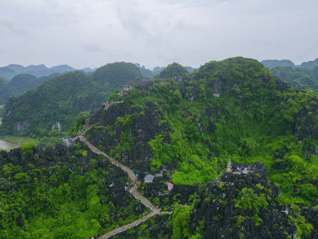 Lush green mountains with a winding path and scattered buildings.
