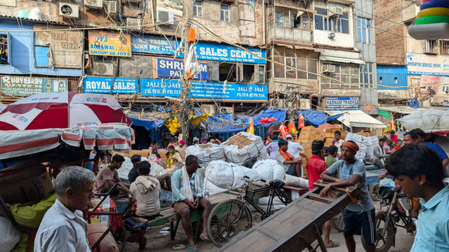 A vibrant and bustling street market in Old Delhi, India, with numerous vendors and shoppers.