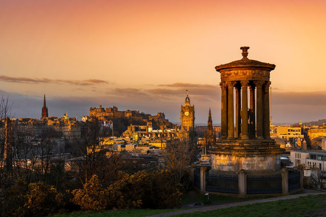 Stunning sunset view of Edinburgh cityscape featuring Calton Hill and historic architecture.