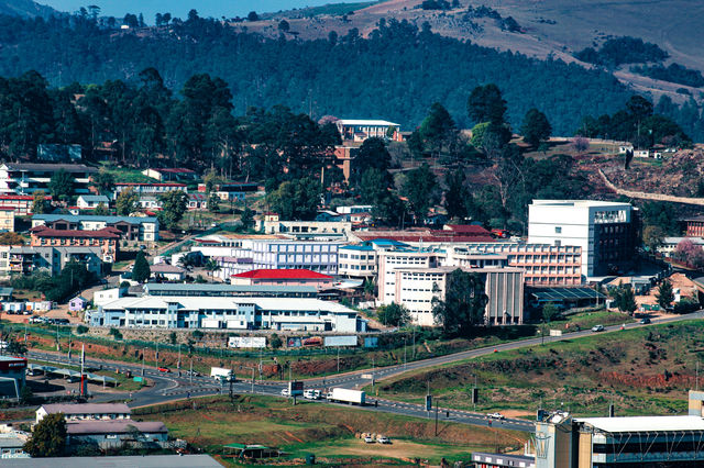 Buildings nestled in a green, hilly landscape.