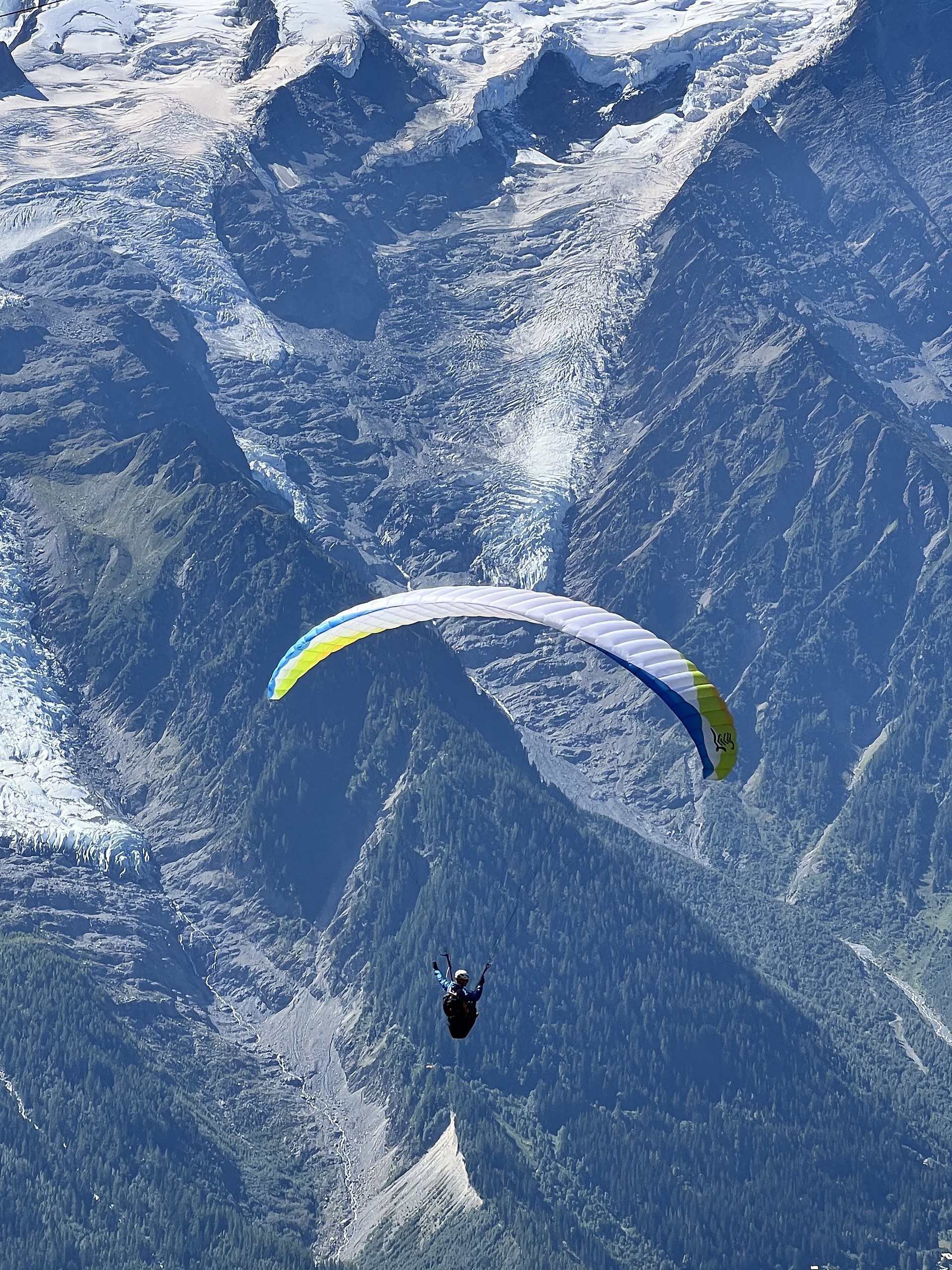 A paraglider soaring above the Chamonix valley with the massif behind