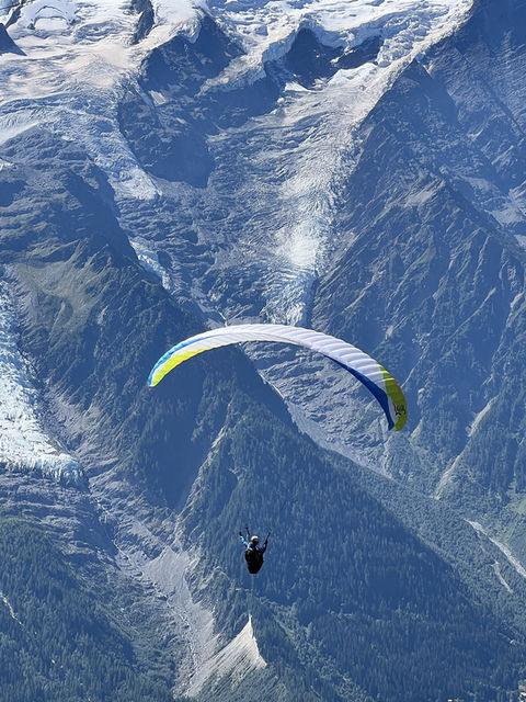 A paraglider soaring above the Chamonix valley with the massif behind
