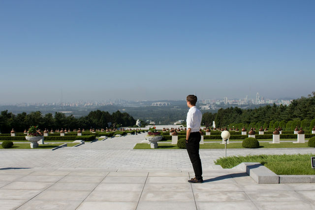 man in white shirt and black pants standing on gray concrete floor during daytime