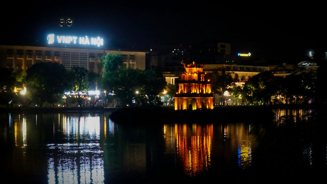 Cityscape at night with illuminated temple and reflections.