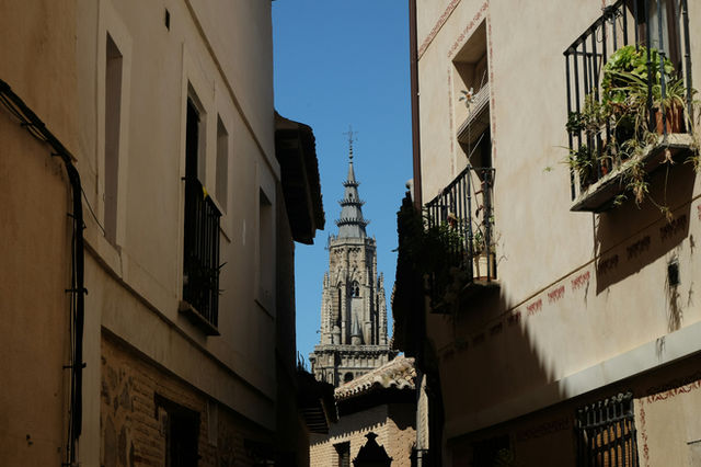 Narrow street with a tall cathedral spire in background