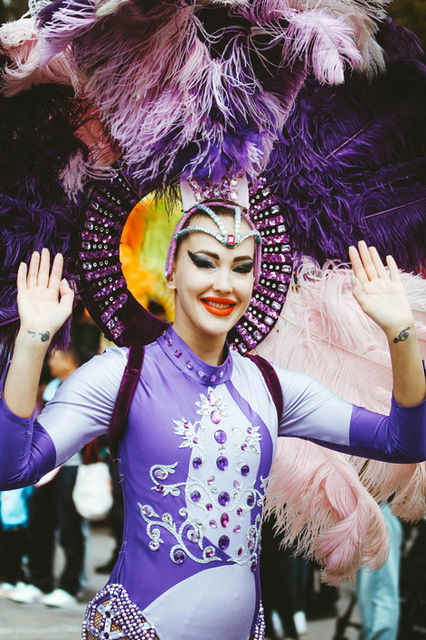 Purple ostrich feathers and a jewelled crown, arms raised