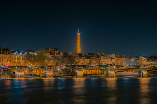 Eiffel tower illuminated at night over the seine river.