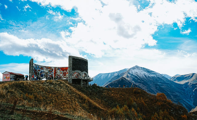 Ruined structure on a grassy hill with mountains behind