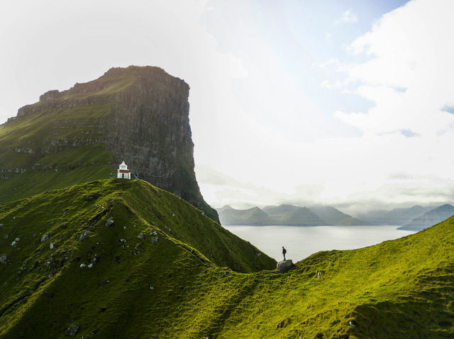 person standing on green mountain during daytime