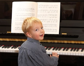 Young boy playing piano music smiling