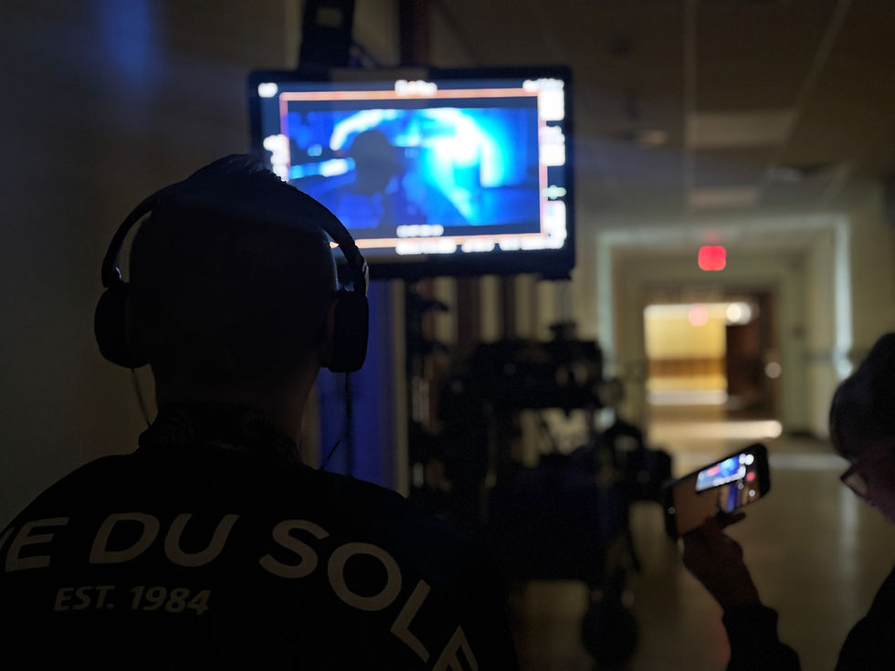A director and script supervisor look at a monitor on the set of a film.