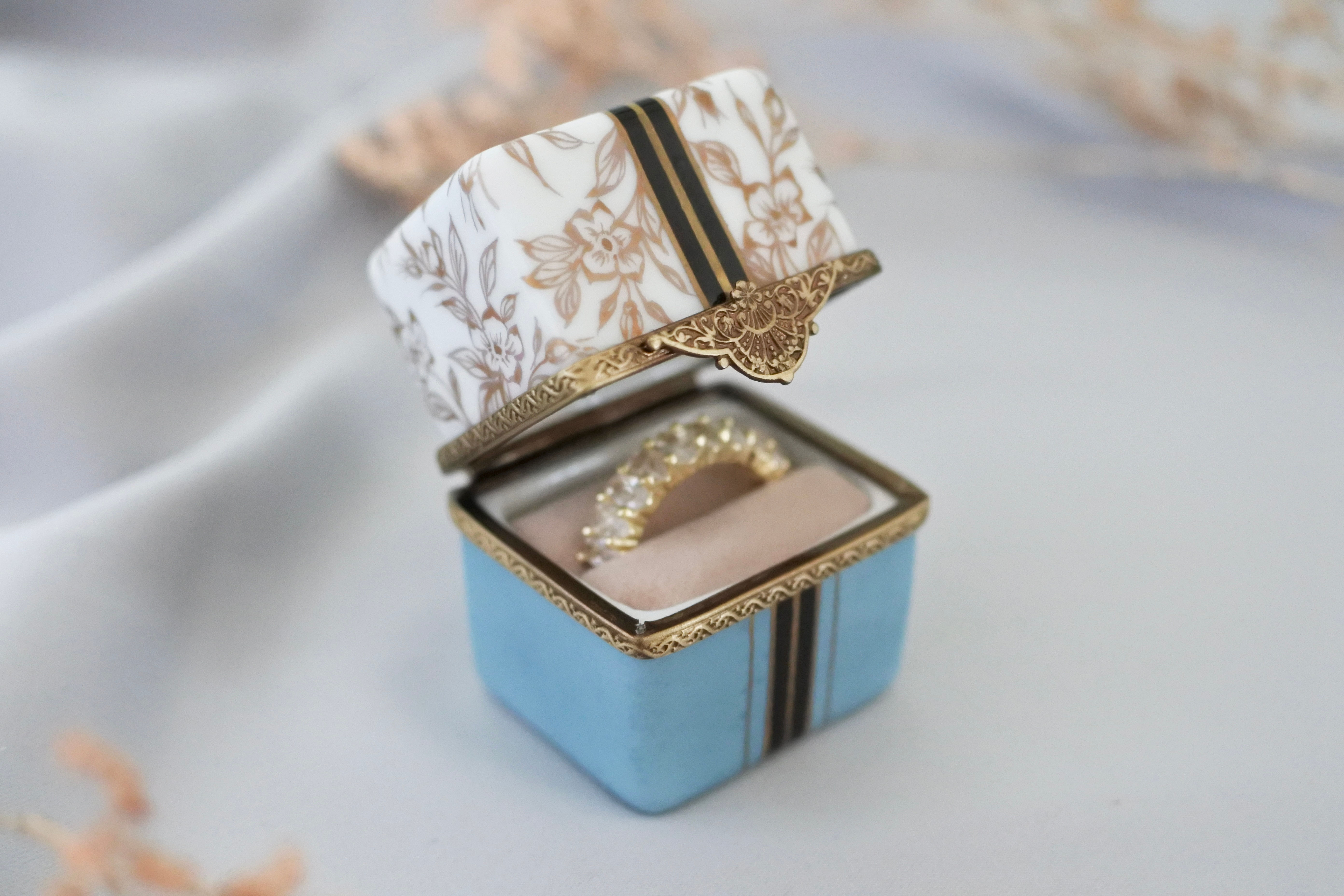 Front view of handmade porcelain ring box slightly open, showing ring inside