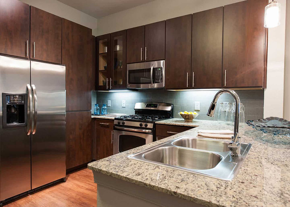 Full kitchen in a Houston furnished apartment with a stove, microwave, refrigerator and double sink