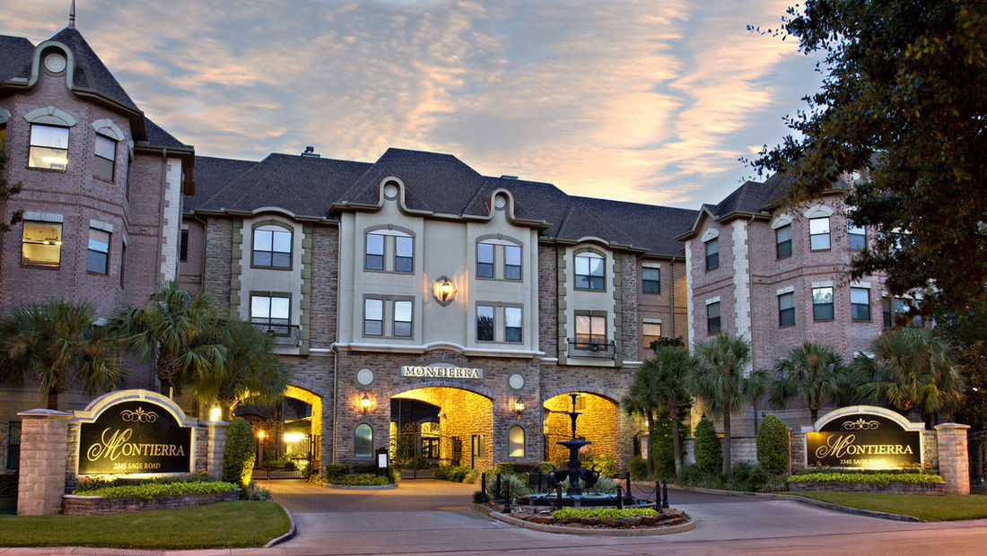 Furnished Apartments Houston offers furnished stays at Montierra: the European-style buildings and fountain entrance at dusk