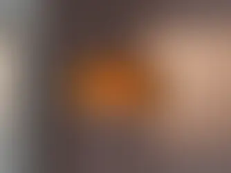 Orange textured pendant lamp hanging in a room with a soft pink wall. A plant is visible in the corner, creating a calm ambiance.