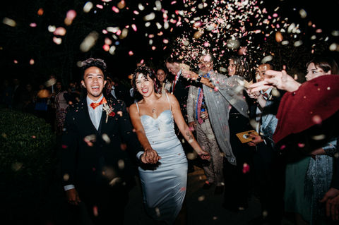 asian bride and groom exiting their wedding with confetti flying in the air