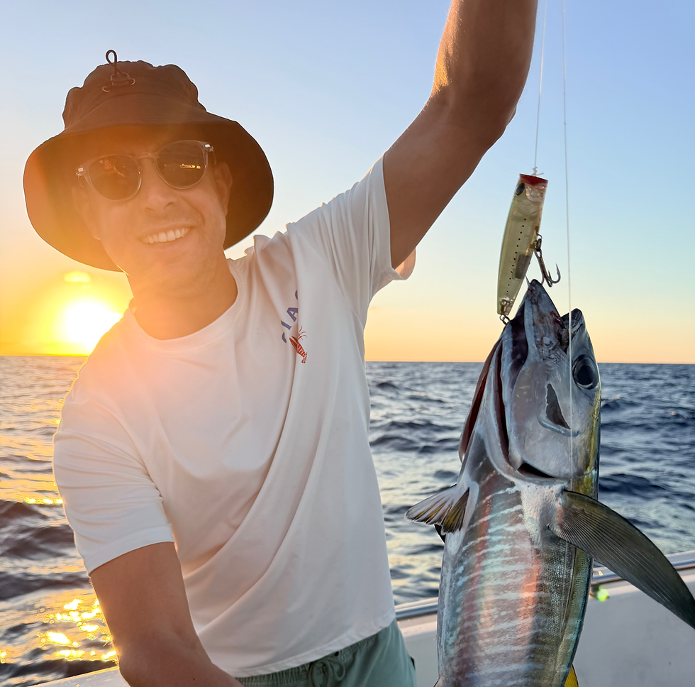 Sortie de pêche au gros : pêcheur tenant un thon à bord au coucher du soleil