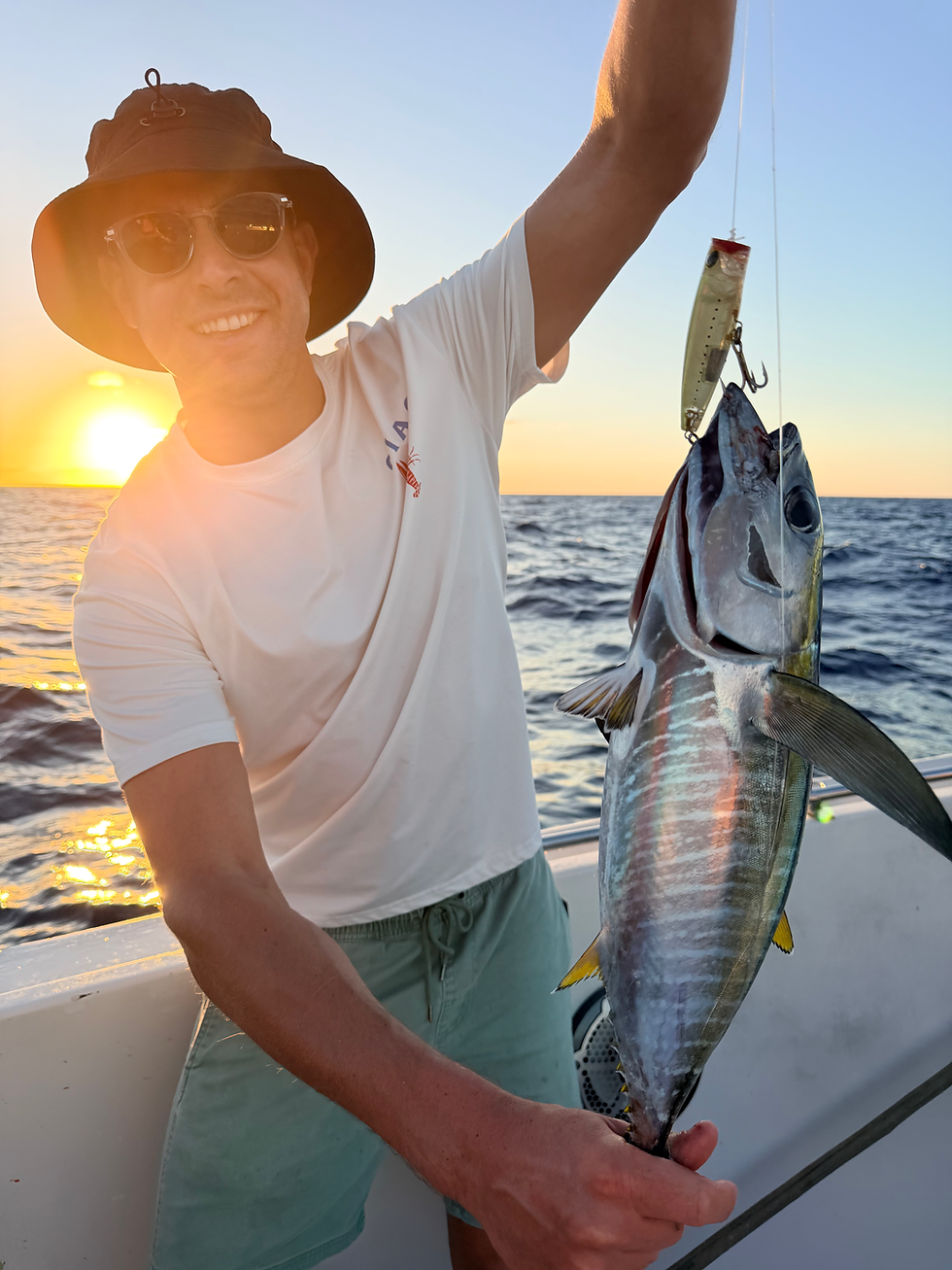 Pêcheur tenant un thon à bord au coucher du soleil