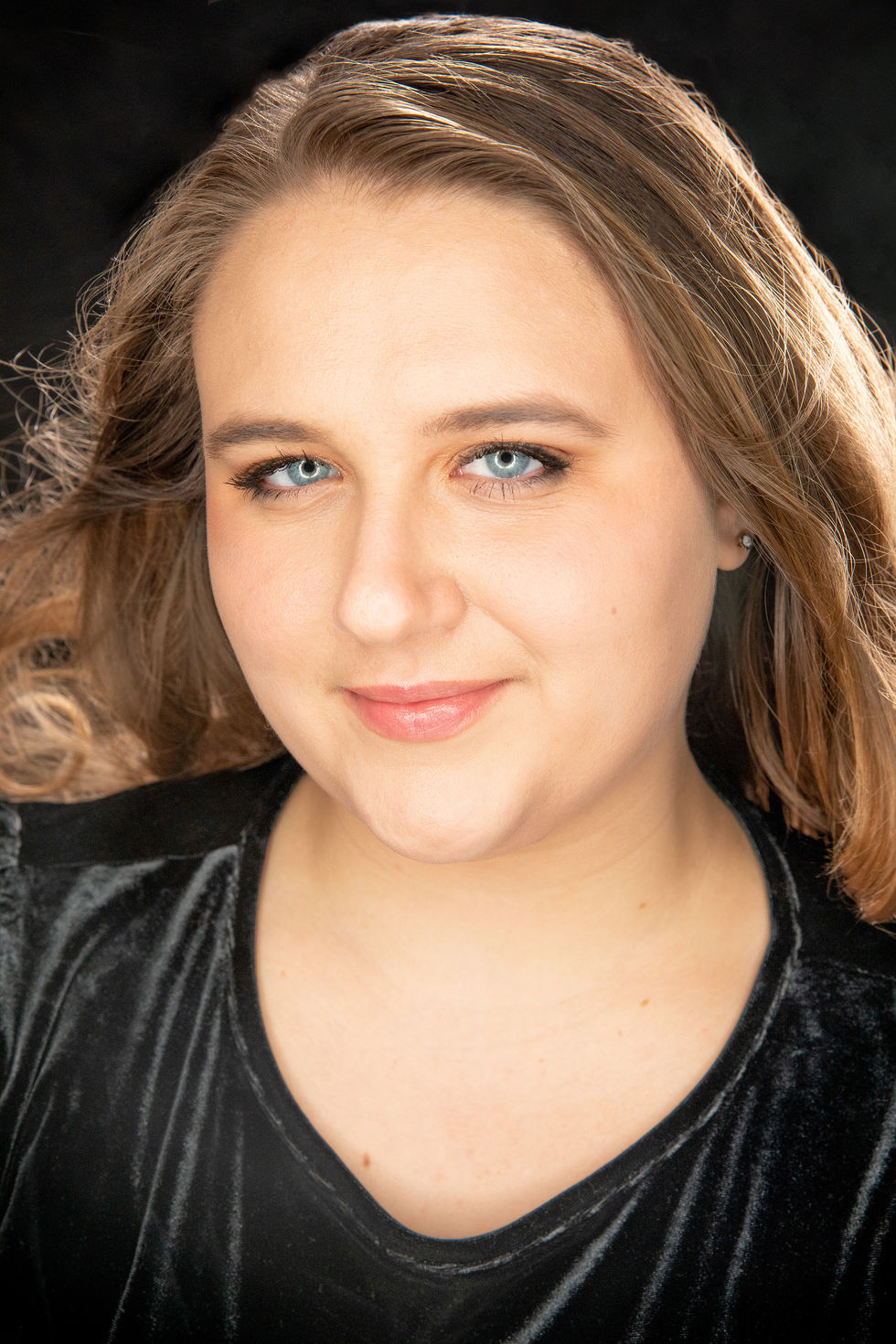 Camri in a black top with long hair and blue eyes looks at the camera