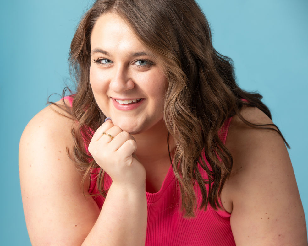 Camri in a pink tank top smiles with her hand on her chin
