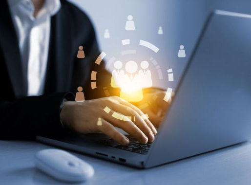 Person typing on a laptop with glowing social media icons above, in a bright, modern setting. Mood is focused and technology-driven.