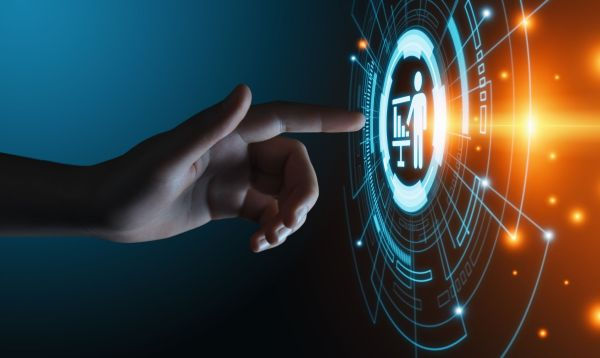 A hand points at a glowing futuristic interface with a person icon on a digital screen. Blue and orange lights create a techy atmosphere.