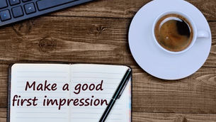 Open notebook with "Make a good first impression" text and a pen on a wooden table, next to a cup of coffee and part of a keyboard.
