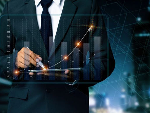 A person in a suit uses a tablet, displaying a glowing bar graph with an upward trend. The background is a futuristic cityscape at night.