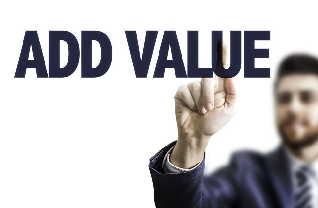 Blurred businessman in suit points upward beside bold navy text ADD VALUE on a white background.