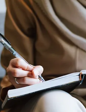 Femme musulmane écrit dans un cahier couleur beige