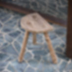 Tabouret tripode ancien en bois massif avec assise demi-lune, patine brute et pieds évasés, style brocante maison de campagne